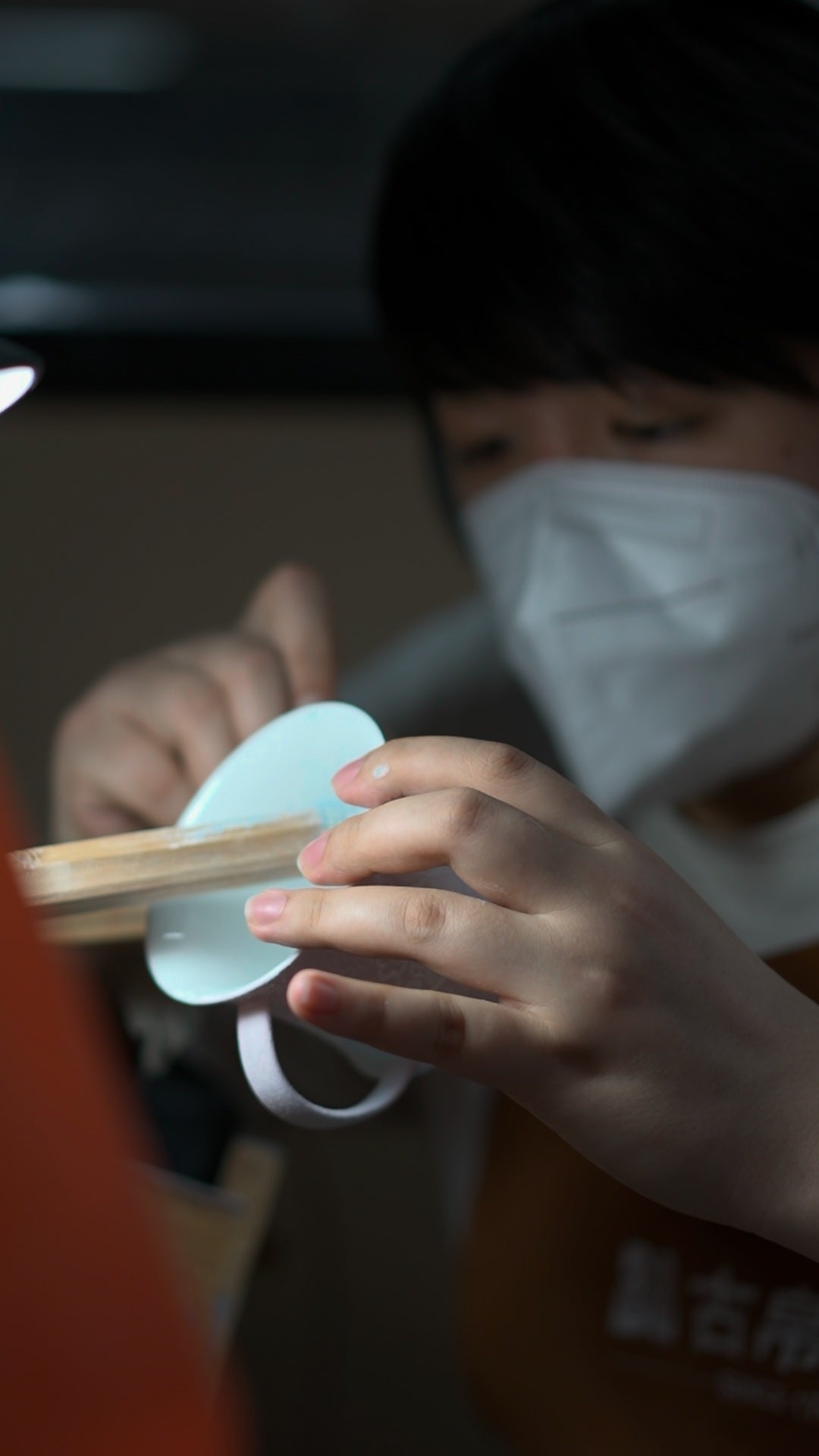 A static photograph of hands working on a porcelain cup with a tool