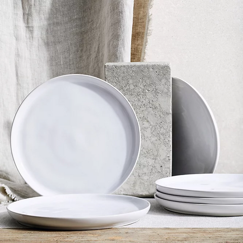 A beautifully arranged dining table featuring an elegant white plate set, highlighting its simplicity and versatility.