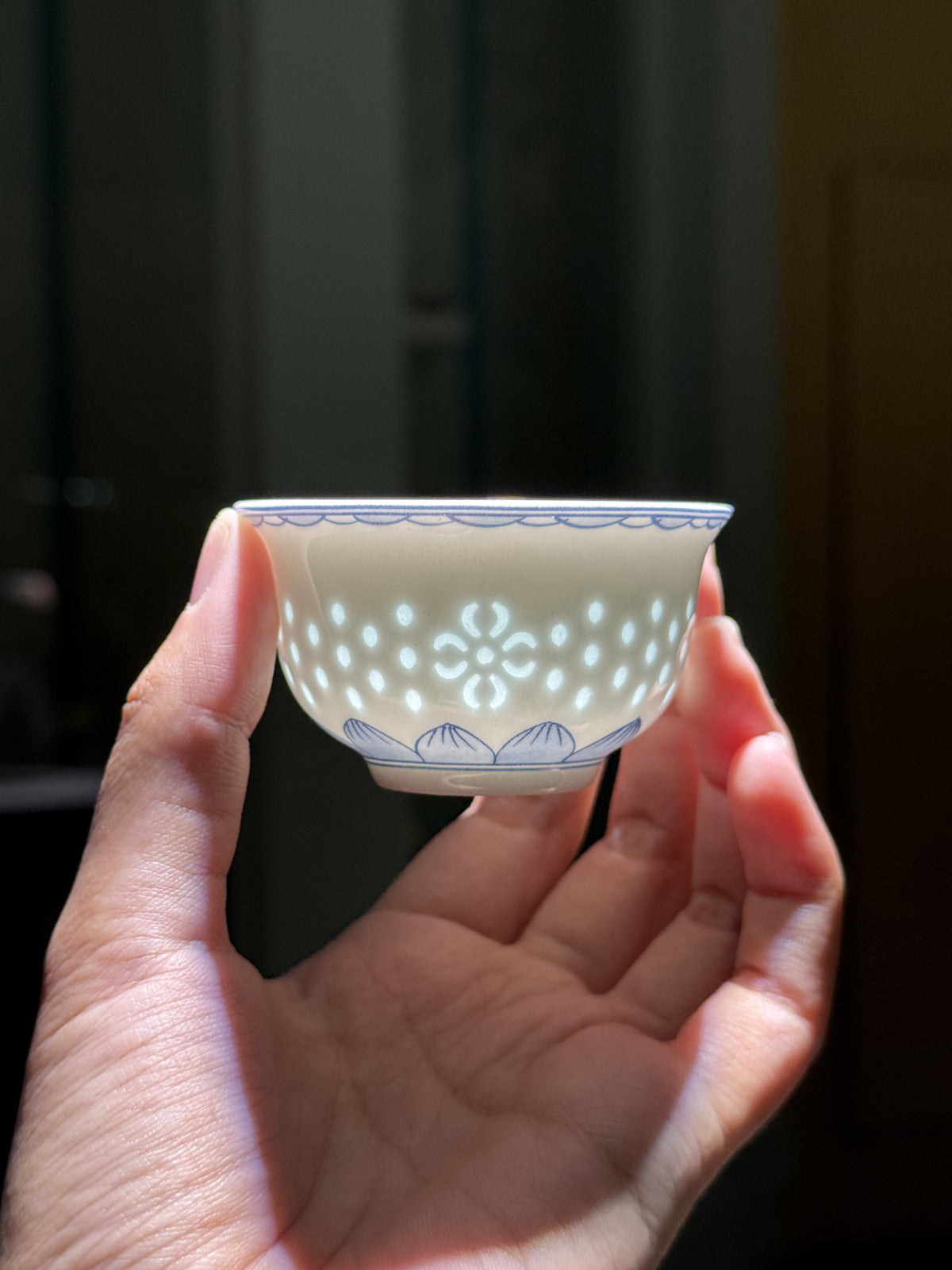 The real Linglong cup held in two hands, showing the original translucent pattern