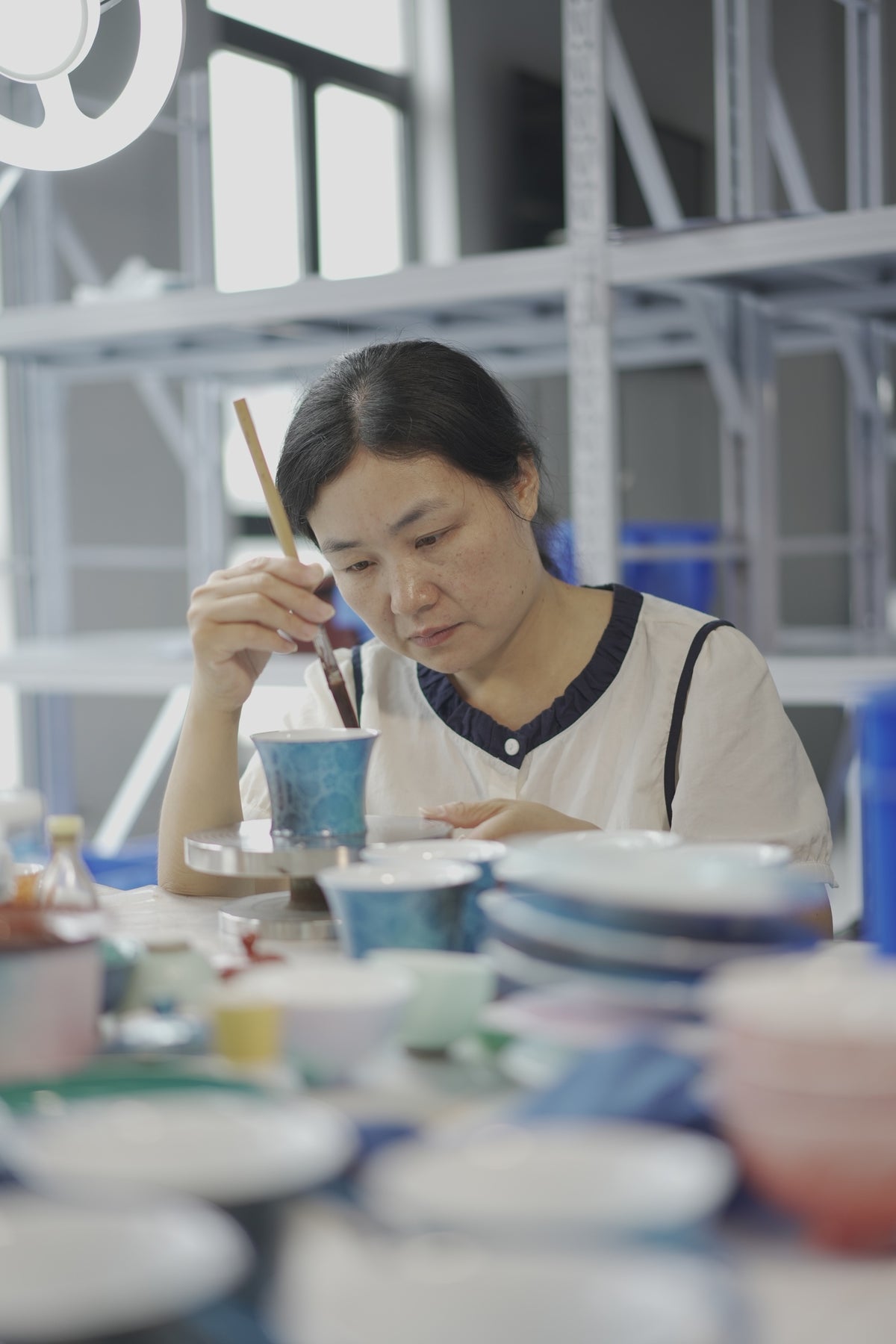 Original Gubo workshop photograph showing work on a turquoise porcelain cup